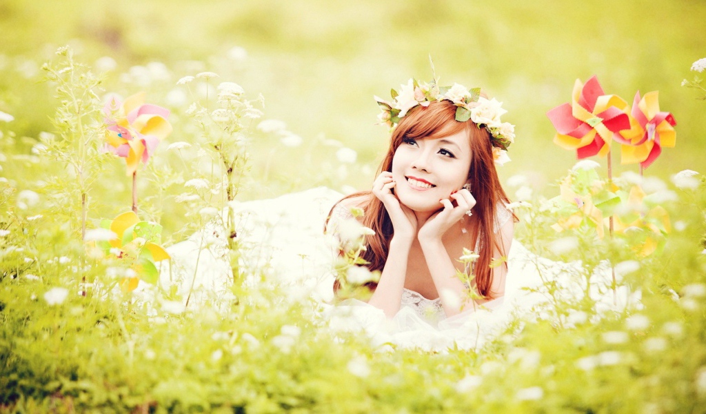 Рыжая японская девушка лежит в поле цветов