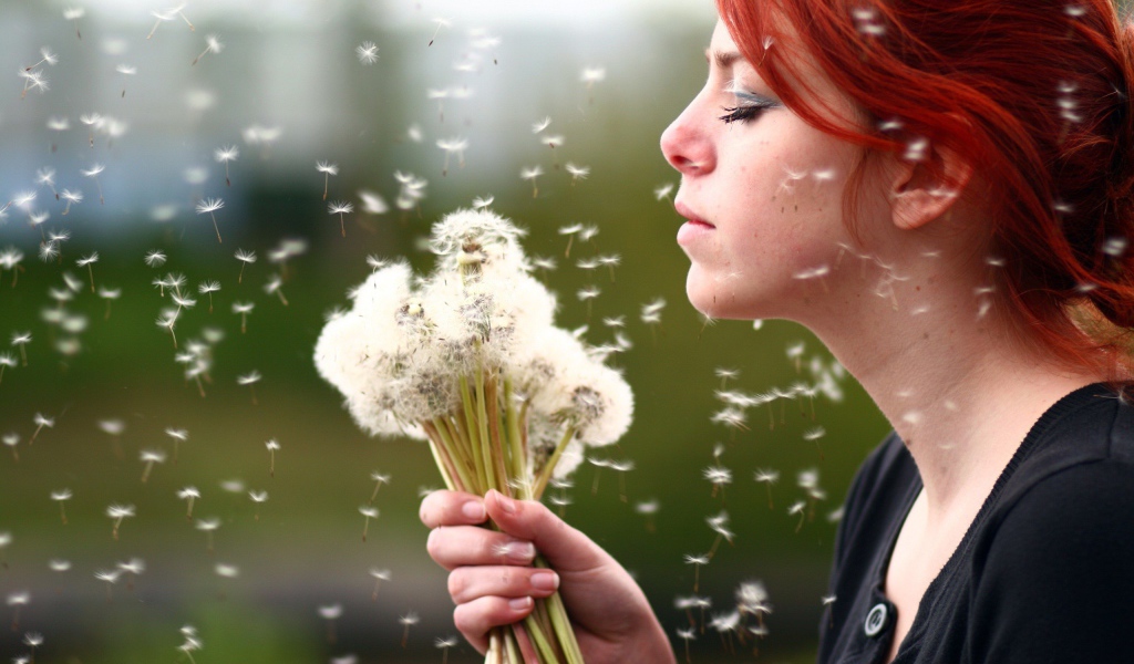 Рыжая девушка с букетом зрелых одуванчиков