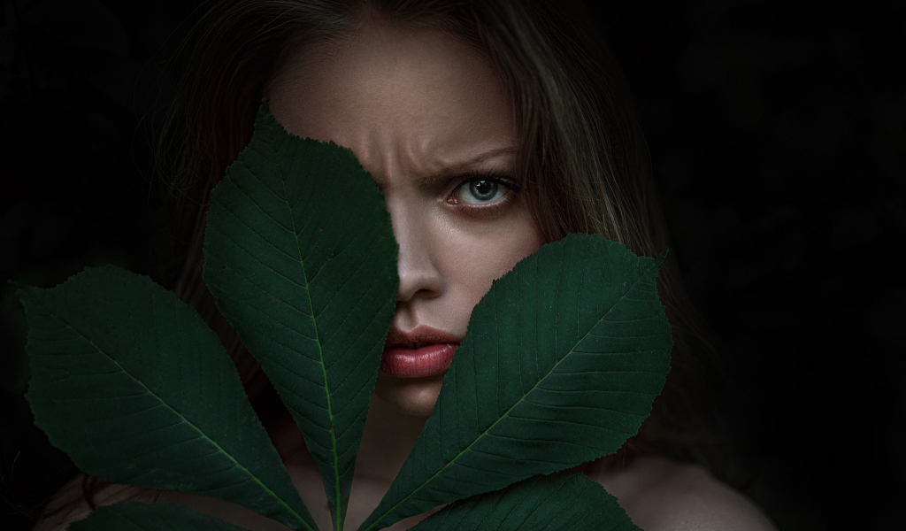 Девушка прикрыла лицо листьями каштана