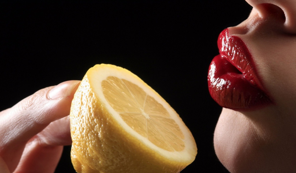 Девушка поднесла лимон к губам
