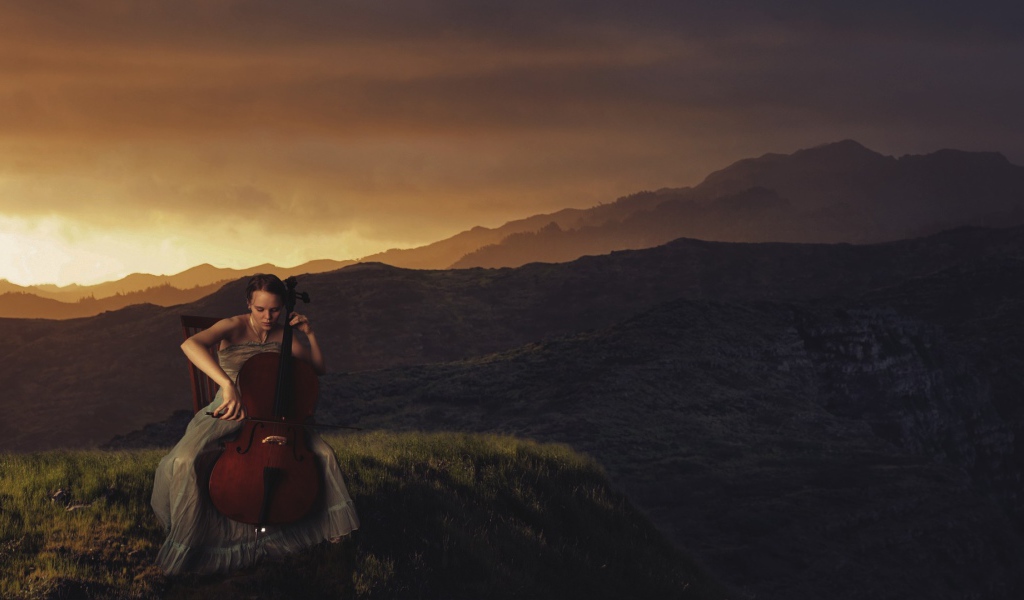 Девушка играет на виолончели на фоне гор