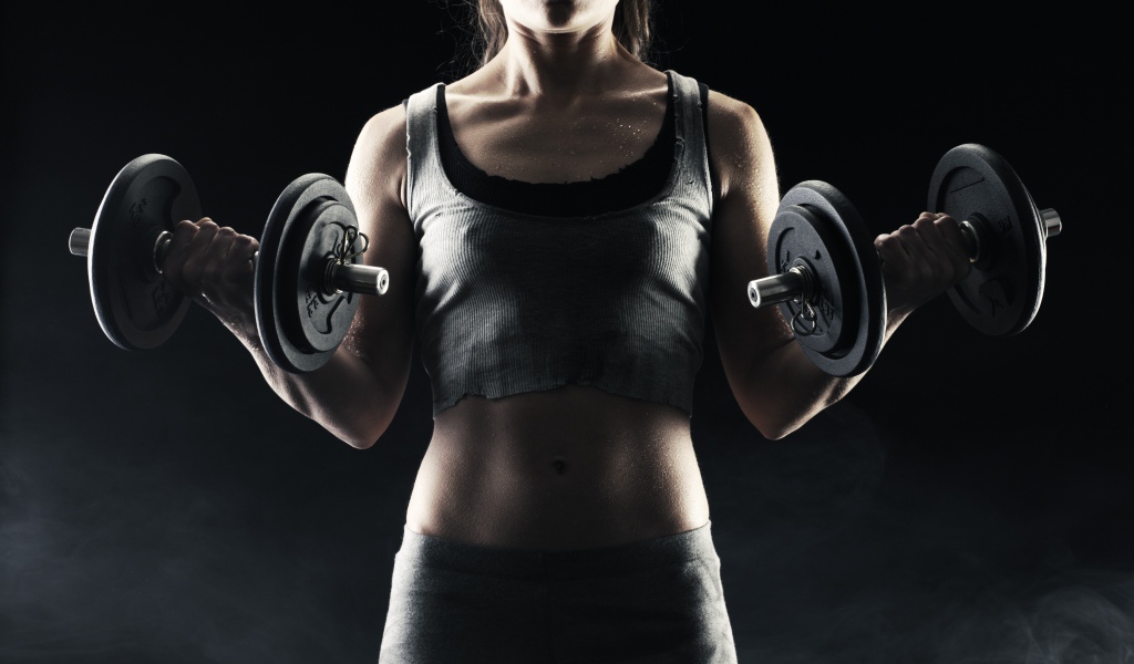 Спортивная девушка с гантелями в руках