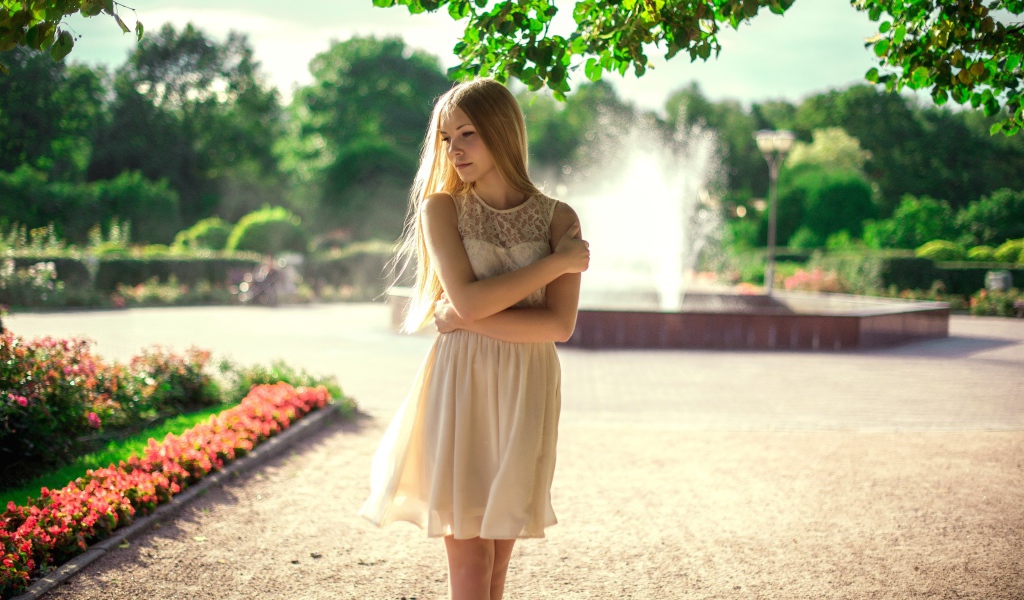Блондинка в парке на фоне фонтана