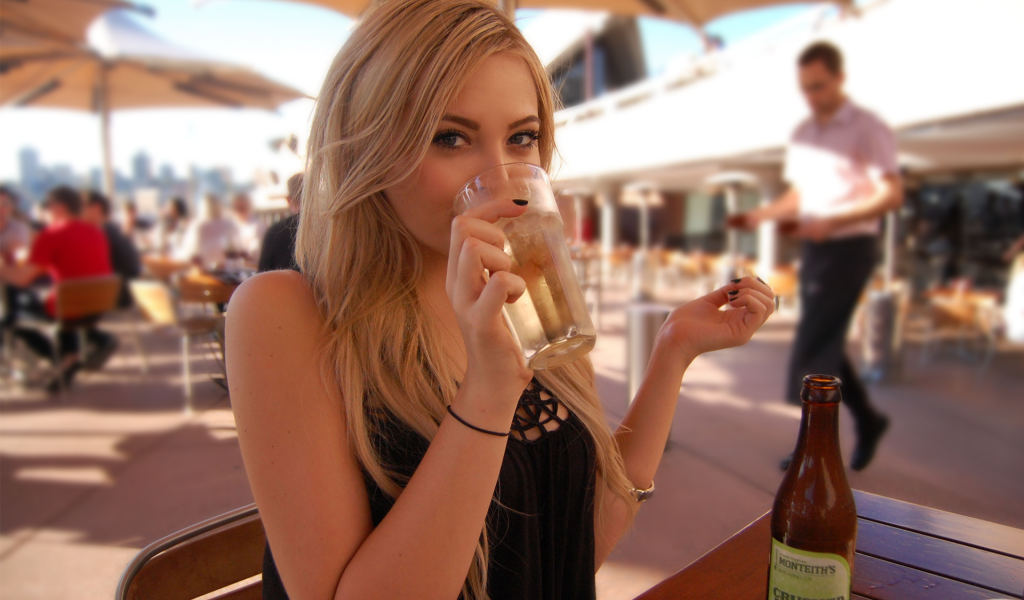 Девушка пьет из стакана в кафе