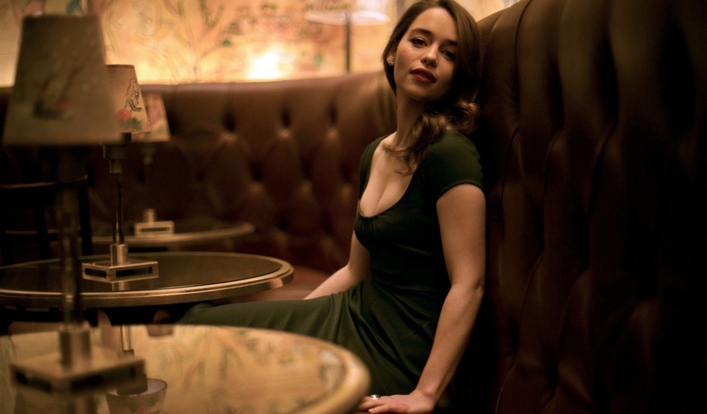 Девушка в зеленом платье сидит на диване