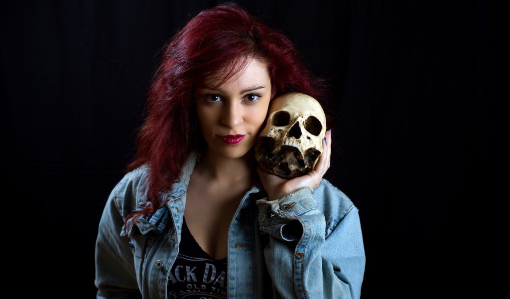 Девушка в джинсовой куртке держит череп на плече