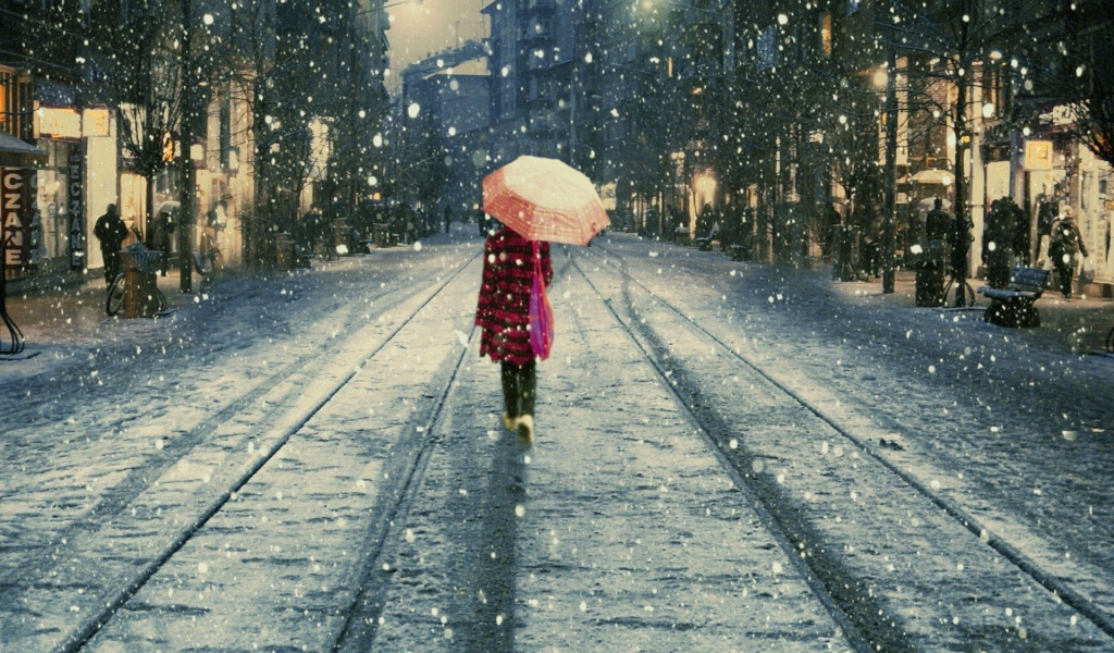 Девушка под дождем идет вдаль по улице