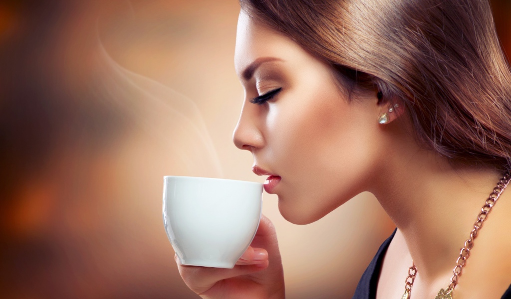 Девушка вдыхает аромат кофе