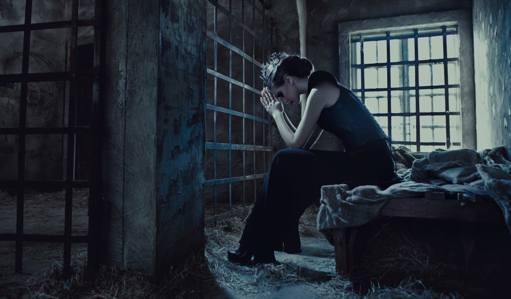 Девушка сидит за решеткой в тюрьме