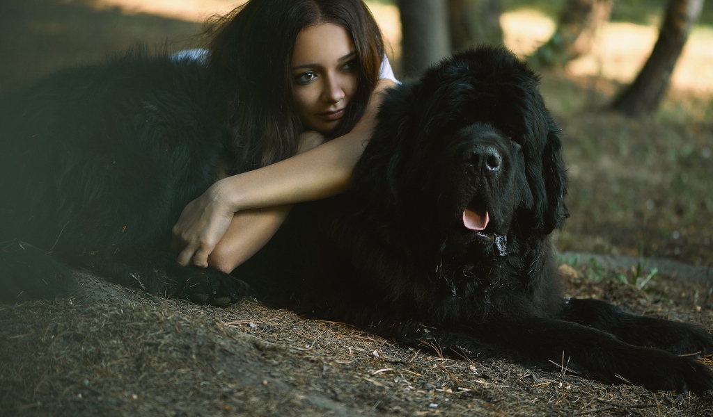Девушка лежит на большой черной собаке