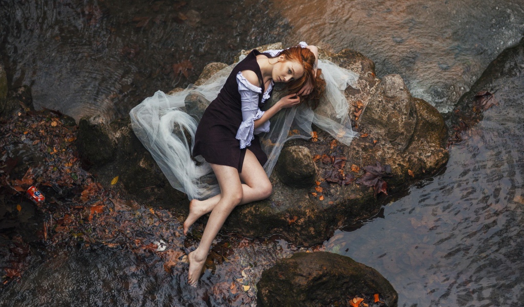 Девушка лежит на камне среди воды