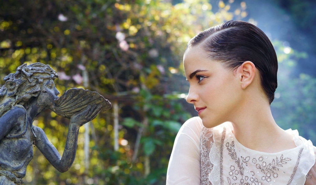 Девушка смотрит на скульптуру в саду