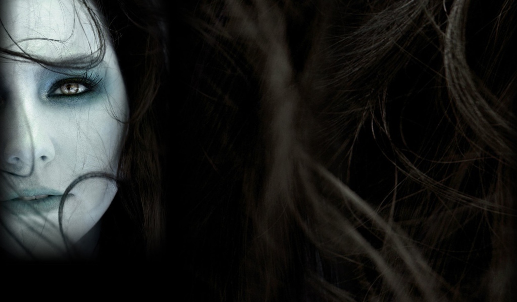 Лицо девушки среди волос на темном фоне