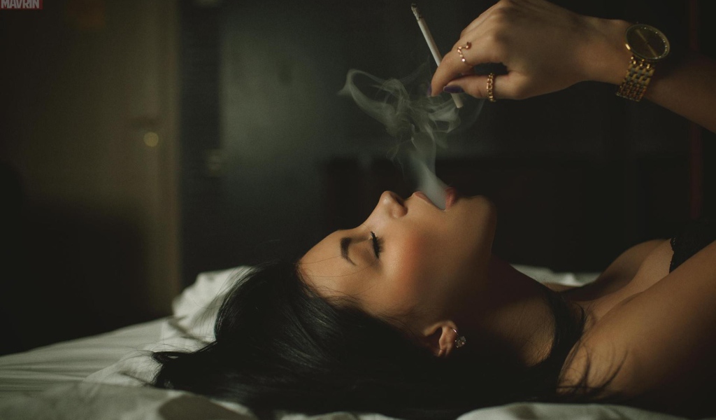 Девушка курит лежа в постели