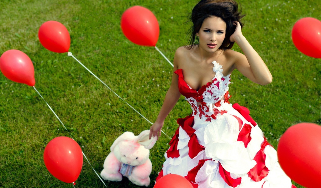Девушка с игрушкой среди красных воздушных шариков