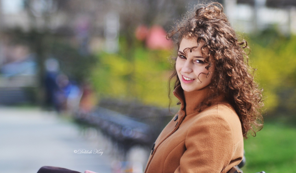 Ветер треплет волосы кучерявой девушки