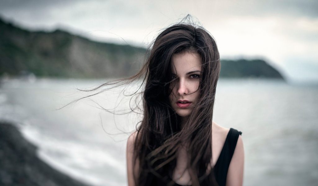 Ветер треплет волосы девушки у моря, портрет