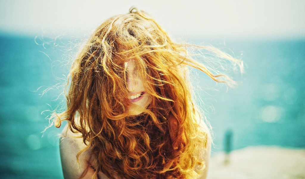 Ветер растрепал рыжие волосы у девушки