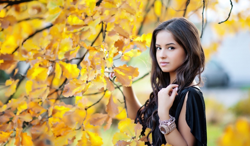 Молодая брюнетка у осеннего дерева