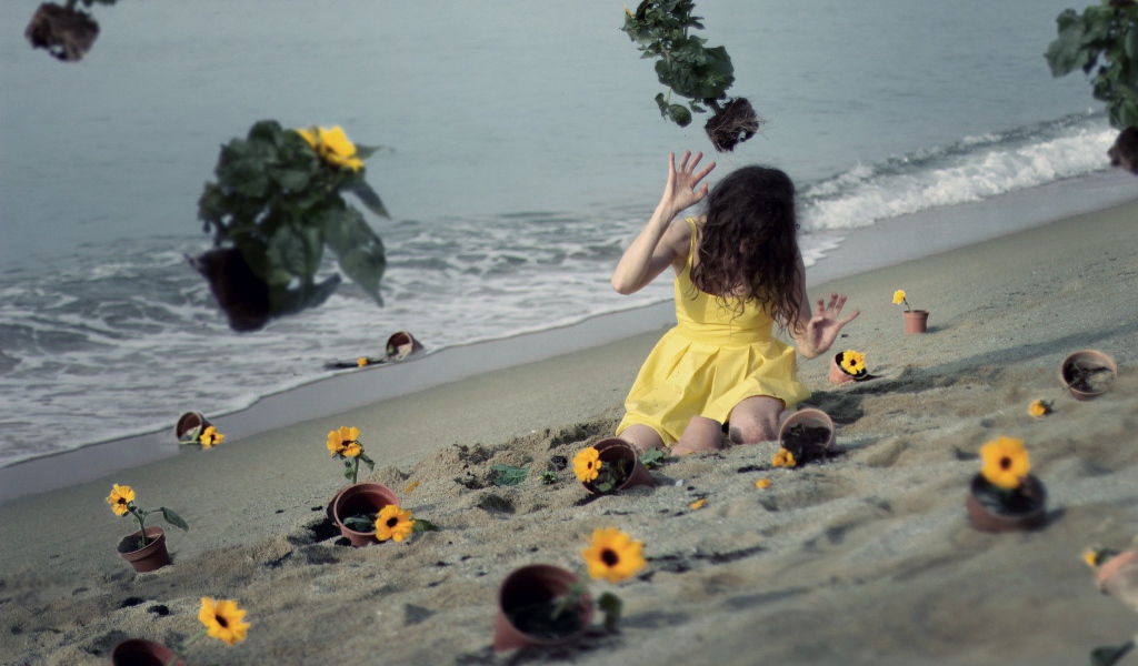 Модель в желтом платье среди цветов на пляже