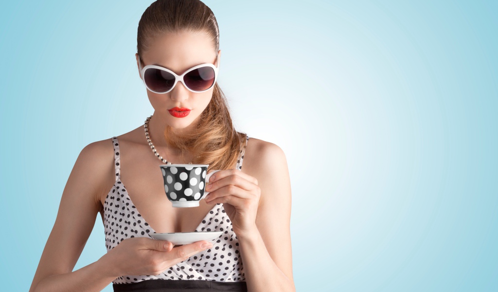 Модель в темных очках с чашкой на голубом фоне