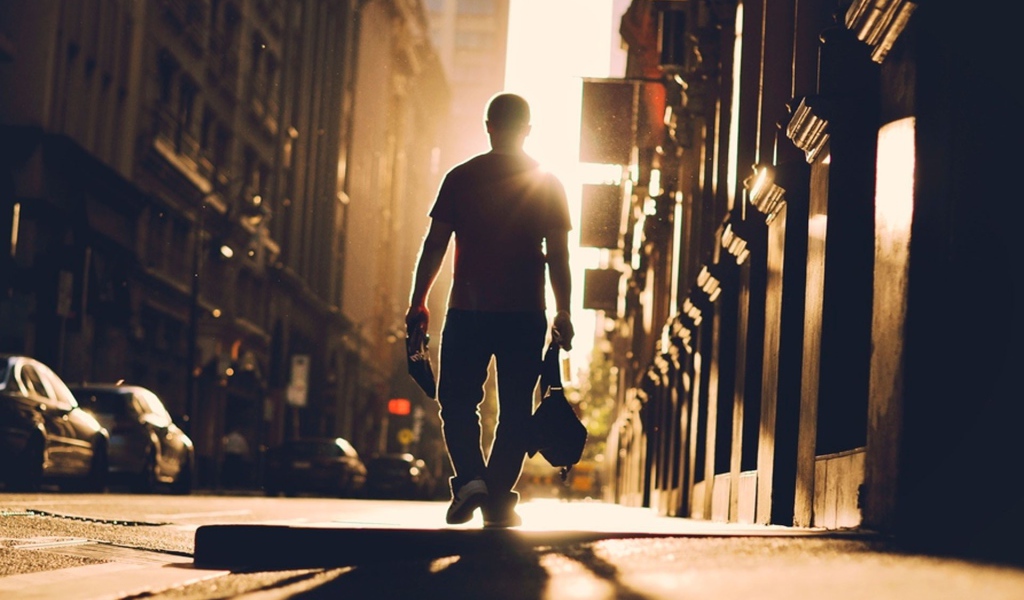 Мужчина идет по улице навстречу солнцу