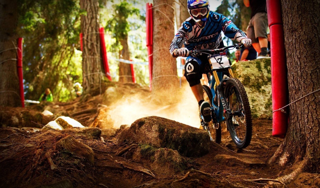 Мотобайкер объезжает камень в лесу