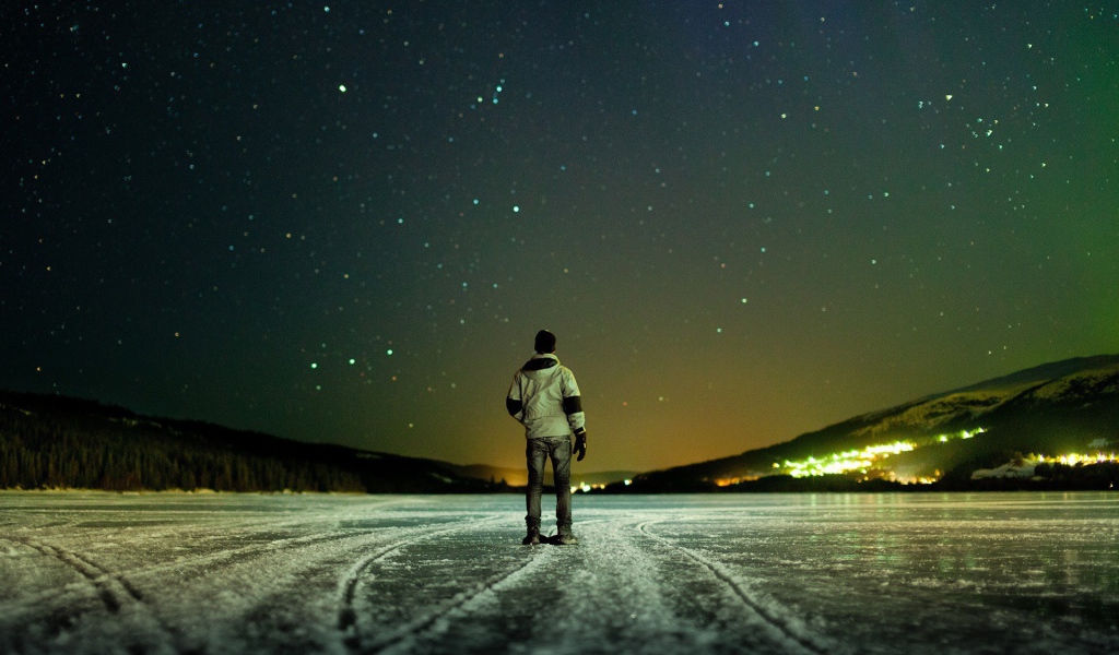 Мужчина на льду смотрит на звезды
