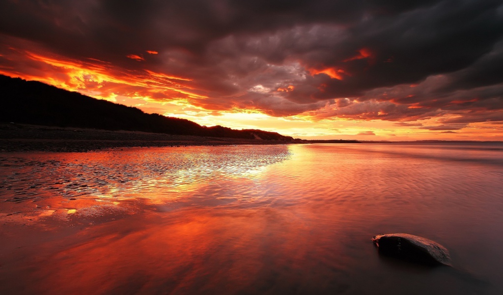 Камень на мелководье на фоне красного заката