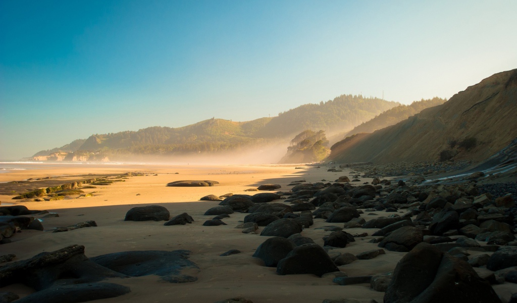 Черные круглые камни на песке пляжа