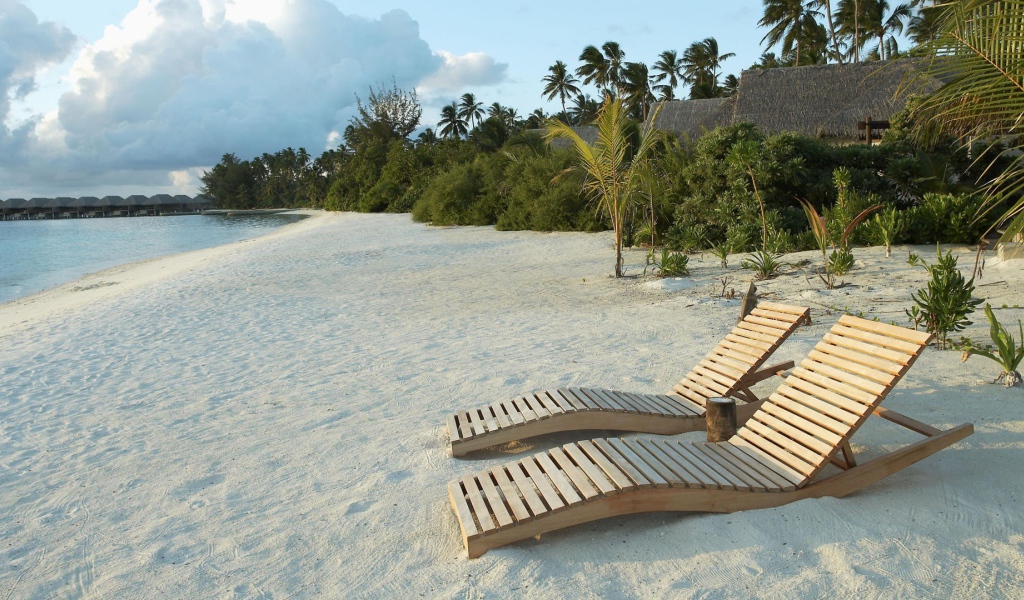 Деревянные шезлонги на белом песке пляжа