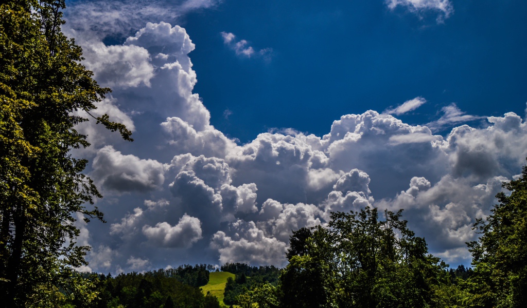 Кучевые облака над зелеными холмами