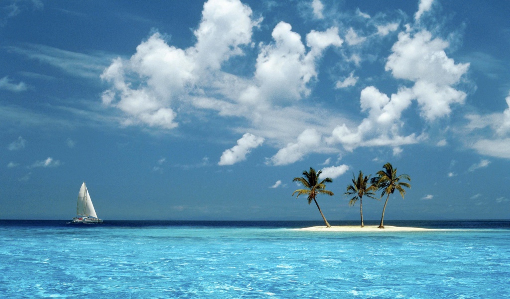 Парусник у песчаного острова с пальмами