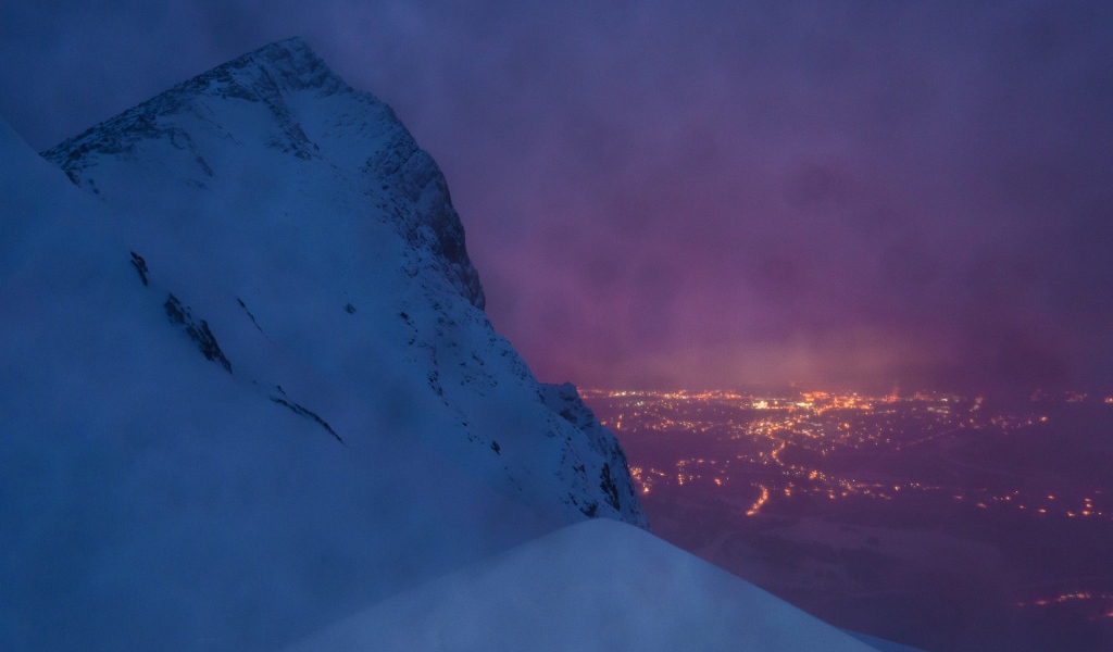 Заснеженная скала на фоне ночного города
