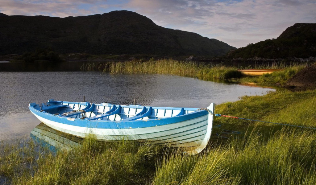 Синяя лодка на берегу озера