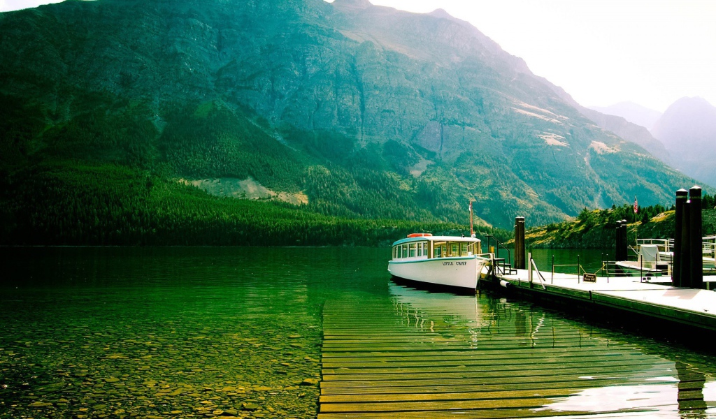Лодка у причала на зеленой воде горного озера