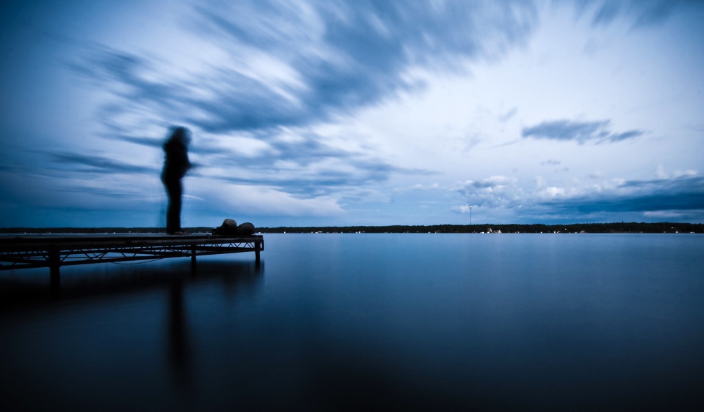 Силуэт человека на пристани у озера