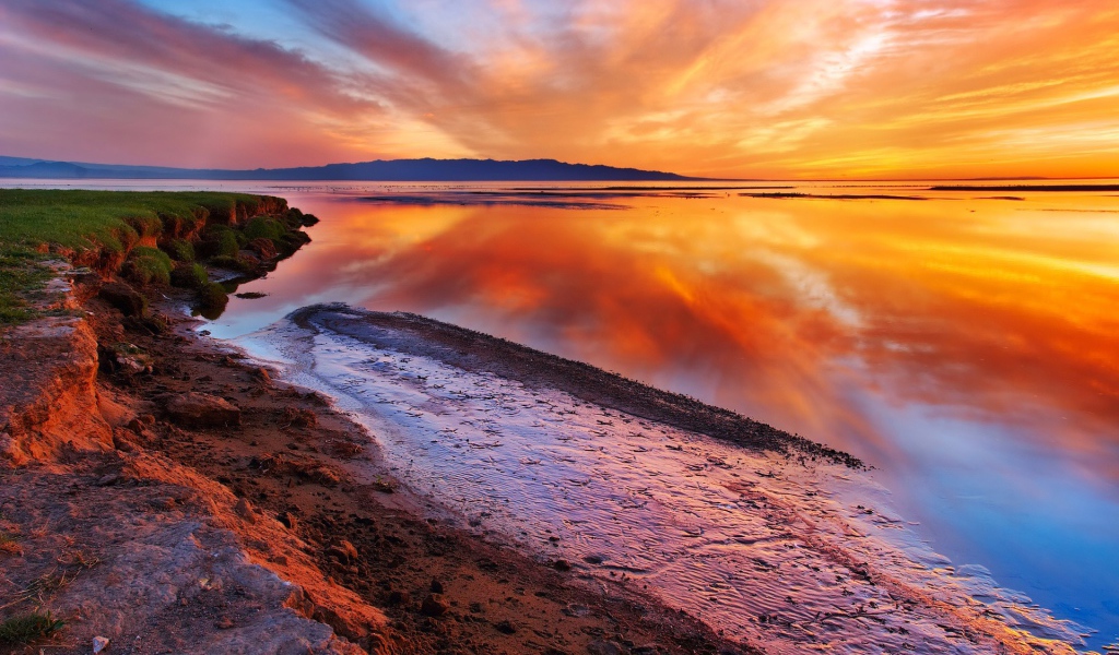 Оранжевые облака отражаются в зеркальной глади воды