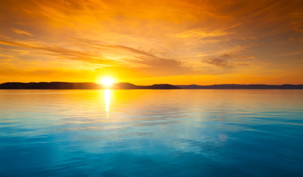 Оранжевое небо над голубой водой на закате