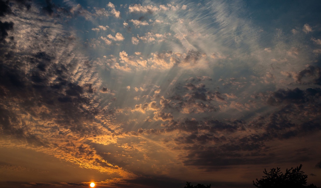 Солнце на закате освещает перистые облака
