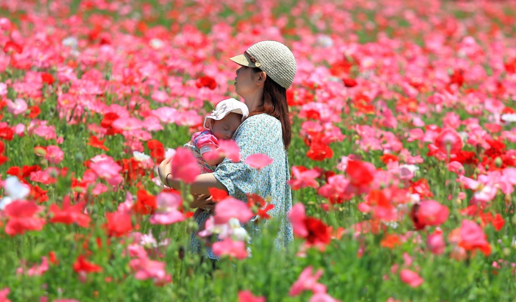 Девушка с ребенком идет по полю цветов