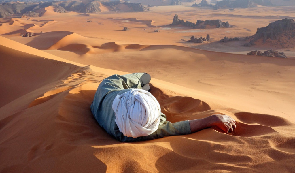 Man lying on the sand in the desert