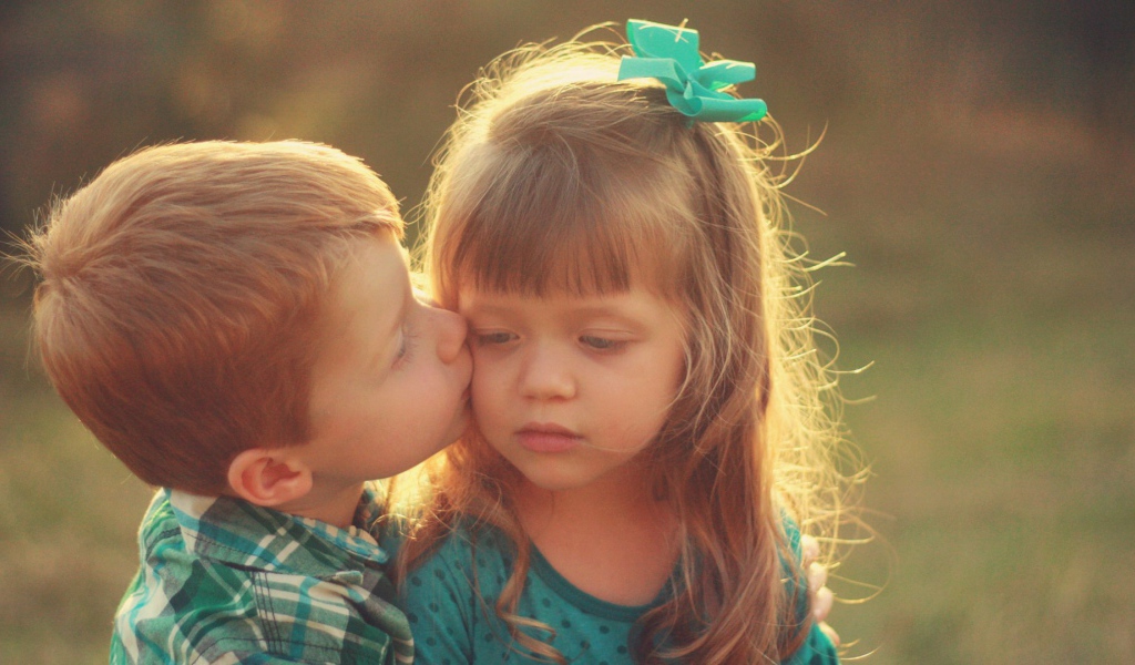 Мальчик целует сестренку в щеку