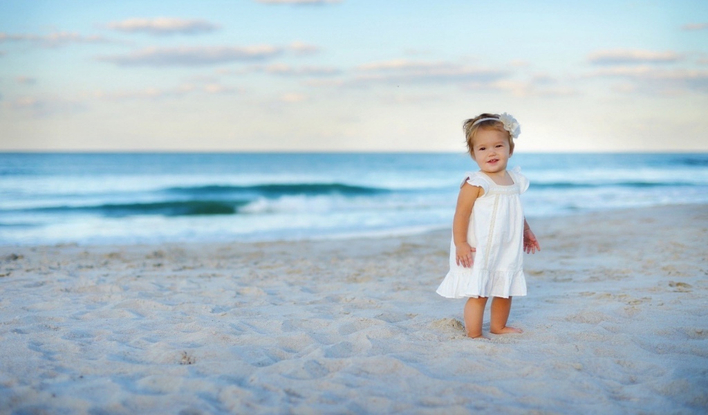 Девочка в белом платье на песке пляжа