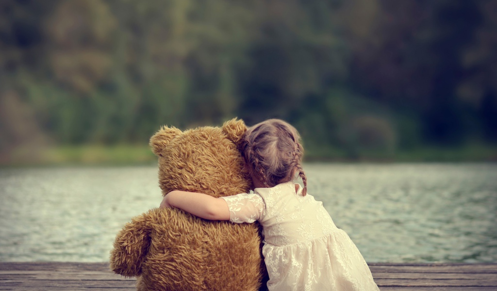 Девочка сидит в обнимку с плюшевым медведем