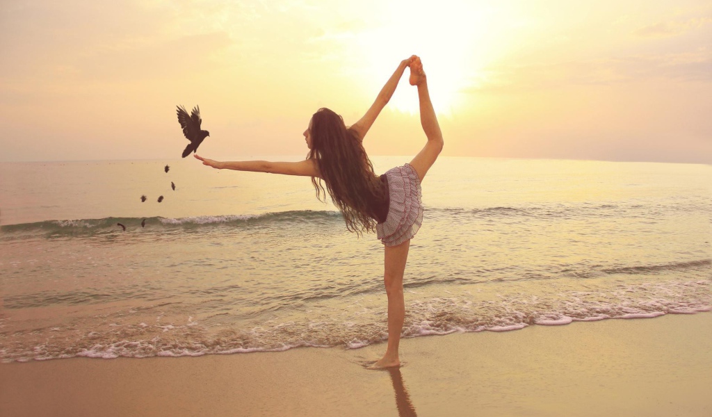 Балерина на берегу моря с птицей