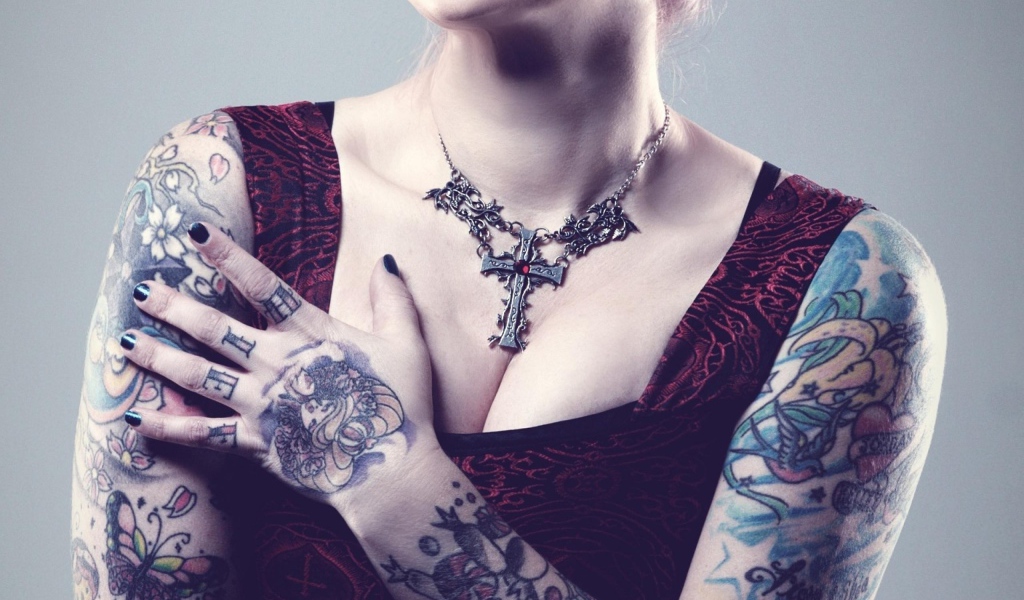 Красивый кулон на груди татуированной девушки