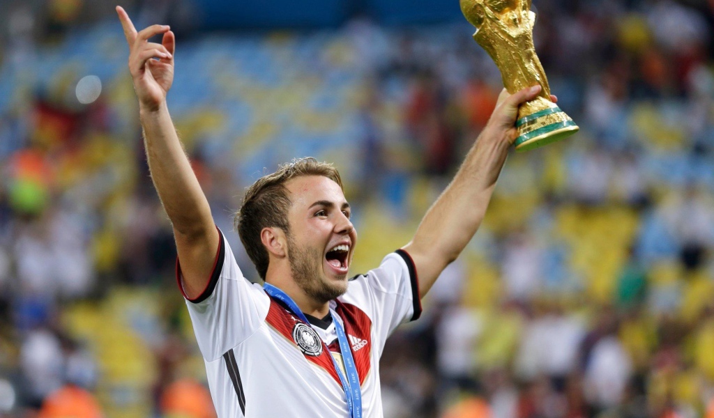 Немецкий футболист Марио Гётце держит в руке кубок