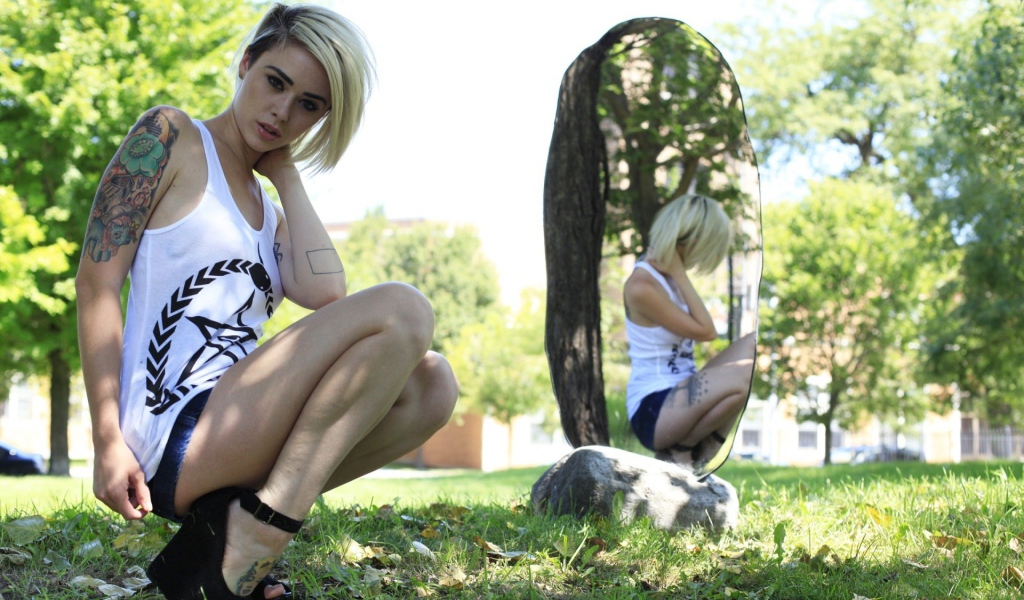 Девушка с тату на природе у зеркала