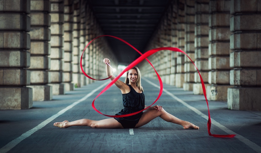 Гимнастка упражняется с красной лентой